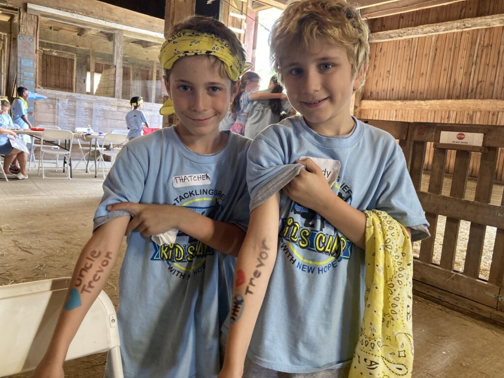 Two participants at camp showing their arms. They wrote their loved one's names on their arms.