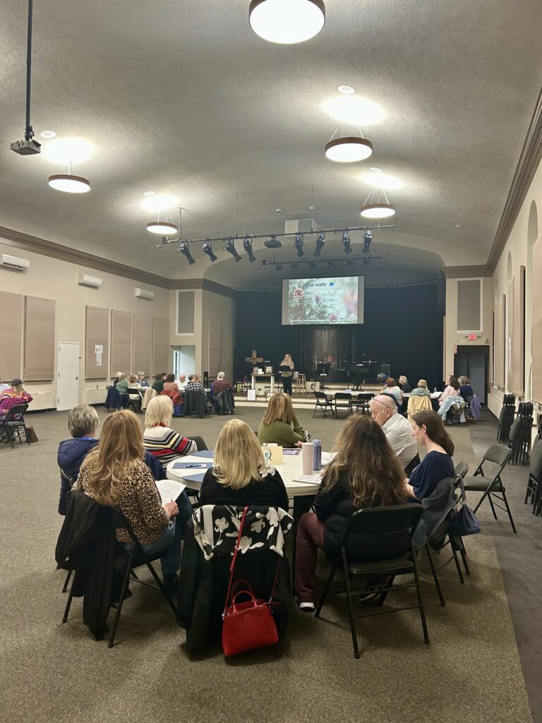 Participants seated at round tables in large room.